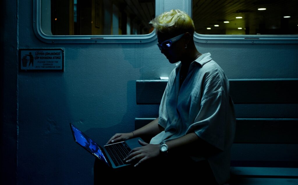 A man sitting on a train using a laptop computer